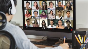 Rear view of Asian businessman working and online meeting via video conference with colleague
